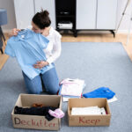 Woman following decluttering tips while organising clothes at home for a minimal living space in Alloa