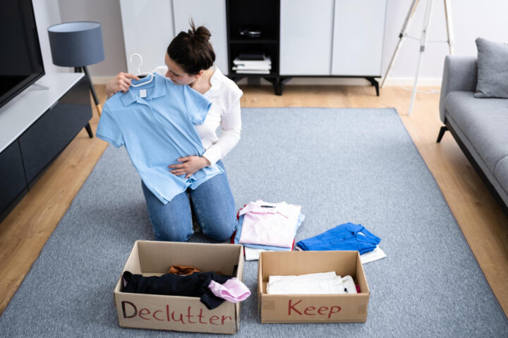 Woman following decluttering tips while organising clothes at home for a minimal living space in Alloa