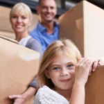 Family preparing for summer travel with moving boxes, illustrating self storage for travelling abroad and protecting belongings while away.