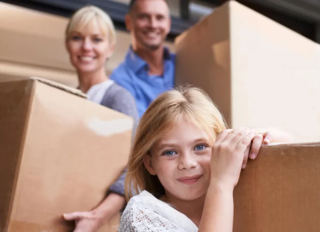 Family preparing for summer travel with moving boxes, illustrating self storage for travelling abroad and protecting belongings while away.