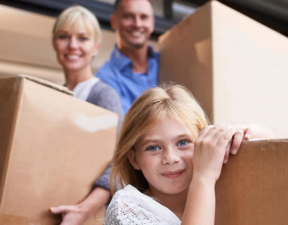 Family preparing for summer travel with moving boxes, illustrating self storage for travelling abroad and protecting belongings while away.